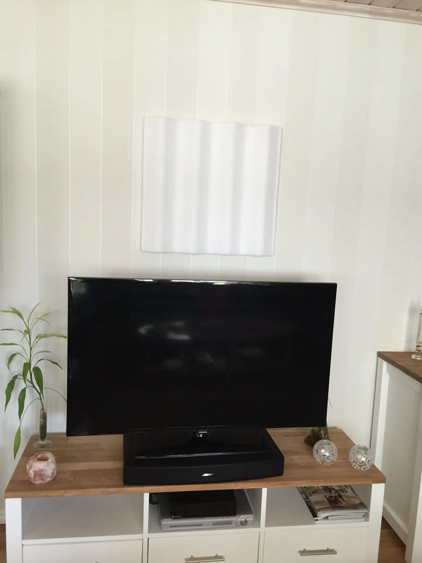 Vit profilerad ljudabsorbent monterad ovanför tv